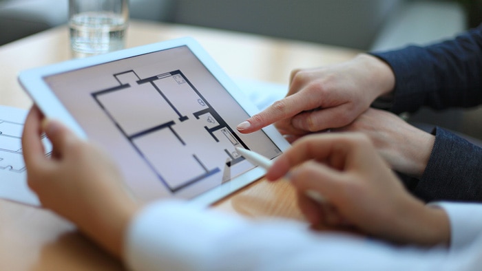 A floor plan displayed on a tablet and a guy pointing to it.
